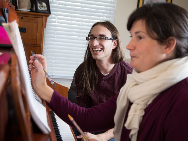 Photo of Danton adjusting music notes for a student at one of his in-home lessons.