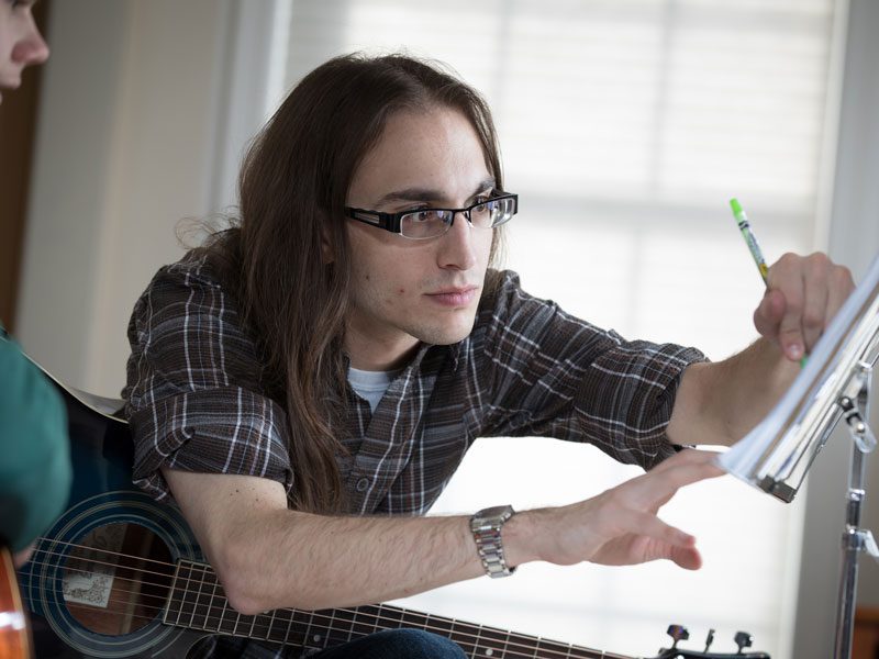 Photo of Danton adjusting music notes for a student at one of his in-home lessons.