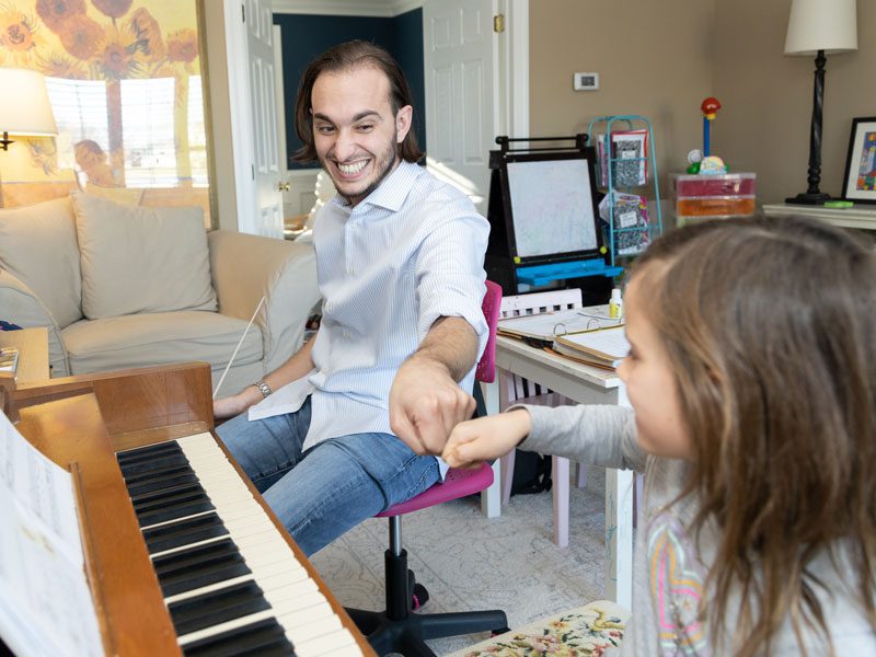 Danton fist bumping a piano student for a private lesson.